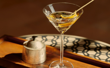 Cocktail served in a martini glass at Amanbagh's bar, with a stirrer and warm-toned backdrop.