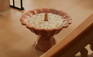 Terracotta bird bath filled with floating flowers at Amanbagh entrance.