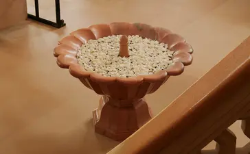 Terracotta bird bath filled with floating flowers at Amanbagh entrance.