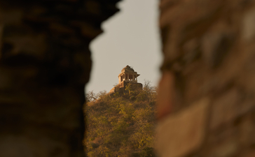 Bhangarh Fort's ancient ruins framed through crumbling stone at Amanbagh, India.