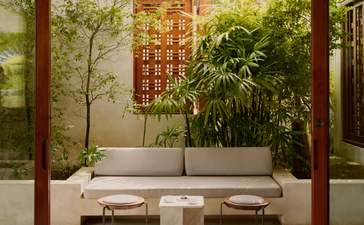Exterior living room at Amanera resort with wooden pavilion, cream seating and verdant garden views.