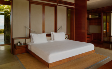 Two-bedroom bay view casa at Amanera with principal bedroom featuring wooden frame bed and warm wood finishes.
