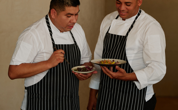 Two chefs in striped aprons review a dish together at Amanera resort's dining venue in the Dominican Republic.