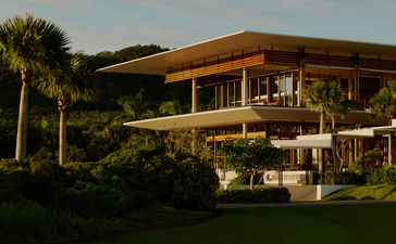 Casa Grande exterior at Amanera resort, Dominican Republic, with curved wooden architecture and palm trees.