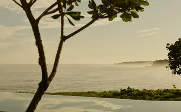 Coastal view at Amanera resort with a solitary tree framing the horizon and seating area below.