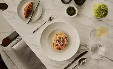 Desayuno servido en mesa blanca con platos de cerámica en Amanera resort.