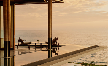 Lounge bar at Amanera Resort overlooking a desert landscape at sunset, with wooden architectural framing and minimal furnishings.