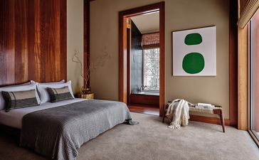 Principal bedroom at Amangani with timber-framed windows and contemporary artwork.