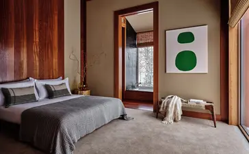 Principal bedroom at Amangani with timber-framed windows and contemporary artwork.