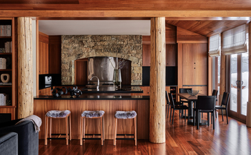 Wapiti home bar and seating area at Amangani, with wooden cabinetry and bar stools overlooking dining space.