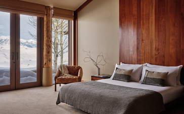 Principal bedroom at Amangani with wooden accents and mountain views through glass doors.