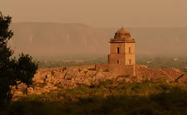 Golden-hued cenotaph rises above the desert landscape at Amanbagh, Rajasthan, at dusk.