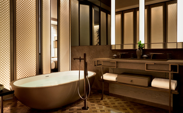 Bathroom in a Premier Suite at Aman New York featuring a freestanding soaking tub and double vanity with warm lighting.