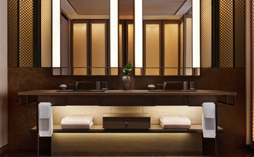 Salle de bains de la suite deluxe, Aman New York, avec vasque intégrée et miroir éclairé.