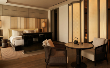 Chambre principale spacieuse à Aman New York avec mobilier élégant et éclairage doré.