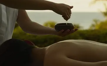 Spa therapist applying treatment to guest's arm overlooking tropical coastline at Amanera resort, Dominican Republic.