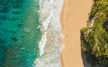 Aerial view of Amanera's coastline with turquoise waters, white sand beach and lush vegetation.