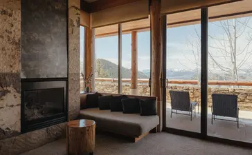 Deluxe Suite at Amangani with fireplace, seating area, and expansive windows overlooking mountain landscape.