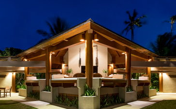 アマンプロのリゾートにある一寝室ヴィラのダイニングパビリオン。夜間照明で暖かく輝く木造建築。