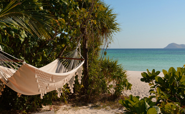 アマンプロ・フィリピンのツーベッドルーム・ヴィラ外観。ハンモックとヤシの木が海辺に面している。