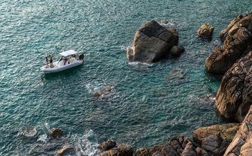 A small fishing boat on turquoise water near rocky cliffs at Amanoi.