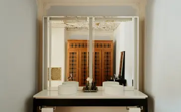Alcova Tiepolo Suite bathroom vanity at Aman Venice hotel, featuring wooden cabinetry and toiletries.
