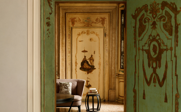 アマン ヴェニスのアルコーヴァ・ティエポロ・スイートのリビングルーム。緑色の装飾扉から奥の部屋が見える。
