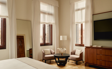 Camera da letto con affreschi presso Aman Venice, con sedute accoglienti e finestre che affacciano sulla città.