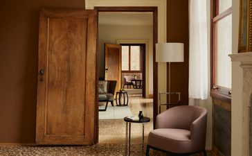 Entrada a la Grand Canal Suite del hotel Aman Venice, con puerta de madera y sala de estar conectada.