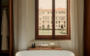 アマン ヴェニスのバスルーム。大運河を望む窓の前に置かれた白い浴槽。