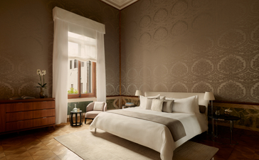 アマン ヴェニスのベッドルーム。運河を見下ろすカナル・グランデの客室で、古典的なベネチアンの装飾が施された穏やかな空間。