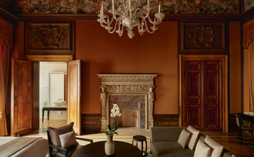 Chambre Sansovino aux murs terracotta et mobilier vénitien classique, Aman Venice.