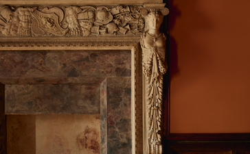 アマン ヴェニスのスタンザ・ベッドルームの暖色の壁と装飾的な石造りの暖炉。