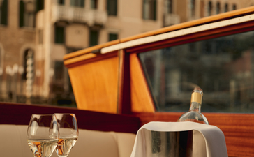アマン ヴェニスのボートでシャンパンを冷やし、ベネチアの歴史的建造物を背景にアペリティーボを楽しむ。