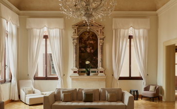 アマン ヴェニスのココチーナス・アパートメントのリビングエリア。シャンデリアと大きな窓が特徴の優雅な空間。
