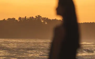 Woman silhouetted against golden sunset over the beach at Amanera resort, Dominican Republic.