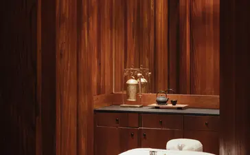 Spa treatment room at Amangani with warm wooden walls and a massage bed draped in cream linens.