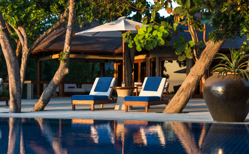 安缦璞乐度假村的三卧别墅外观，泳池旁设有日光浴床和树木。