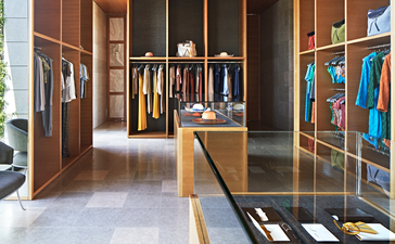 アマンゾイのリゾート内ブティックで、木製ハンギングラックに衣類が展示され、明るい照明と現代的なインテリアが特徴。