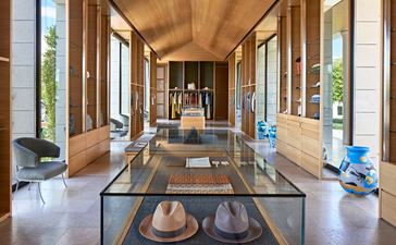 Boutique principale d'Amanzoe, avec vitrines en verre et allée centrale, offrant une vue sur la résidence grecque.