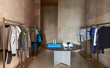 Spa boutique at Amanzoe resort displaying clothing on wooden rails and a blue display table.