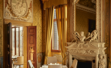 アマン ヴェニスのホテル内にある、金色の装飾と暖炉を備えた優雅なラウンジ。