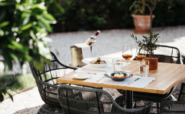 Al fresco dining table at Aman Venice with served dishes and potted plants in Italian courtyard.