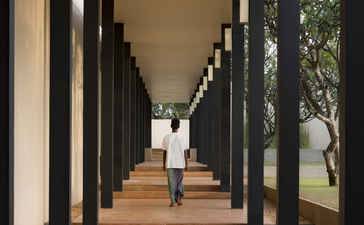 Covered walkway with black columns at Amanwella, Sri Lanka resort, leading towards natural light.