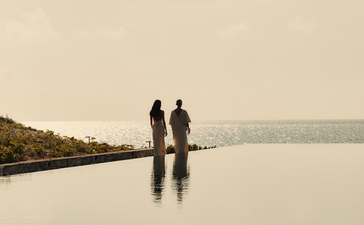 Women by the pool overlooking the sea at golden hour