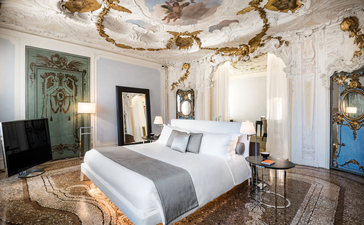 Alcova Tiepolo Suite principal bedroom at Aman Venice, with ornate ceiling frescoes and period furnishings.