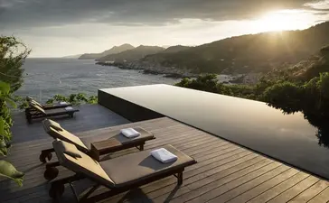 One-bedroom ocean pool residence with wooden deck overlooking Amanoi's serene coastal waters at sunset.