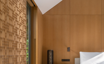 Amanyangyun bedroom with wooden panelling, brick accent wall and bed with white linens.