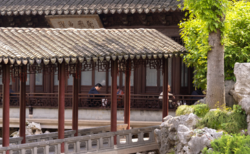 Traditional Chinese pavilion with dark timber framing at Amanyangyun, stone bridge and garden in foreground.