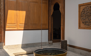 Sunlit courtyard at Amanyangyun with wooden doors, brass bowl, and traditional Chinese architectural details.